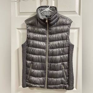 Silver fashion puff vest with expandable sides.